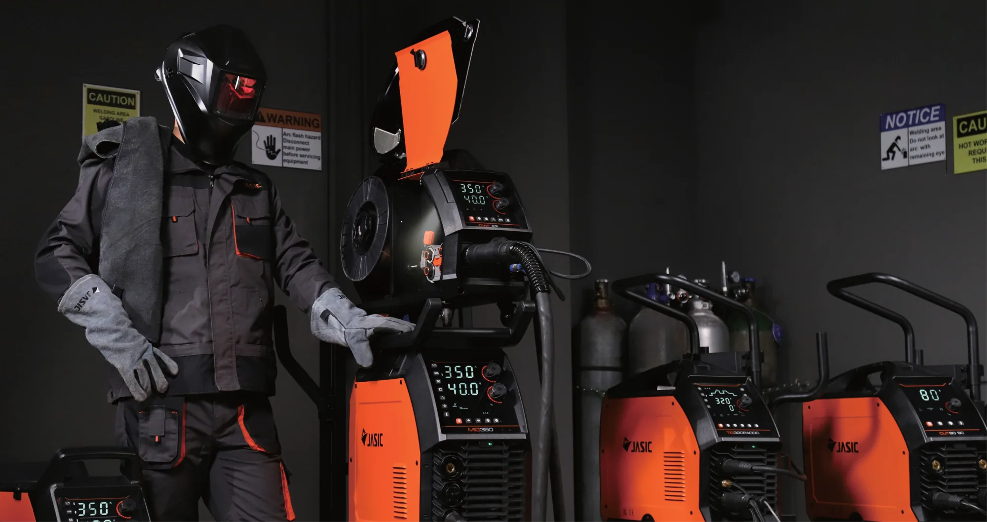 Home 1 Welder in full PPE beside Jasic MIG, TIG and plasma cutting machines in a workshop